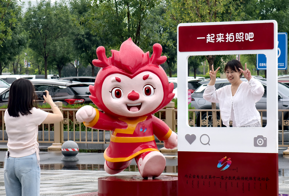 7月25日,两名导游在赤峰机场前的赛会吉祥物雕塑处留影。曹政 摄