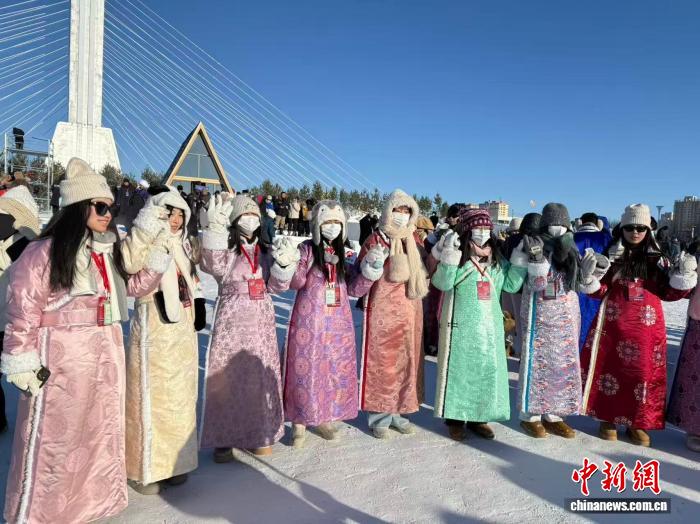 2025年12月21日,内蒙古呼伦贝尔,身着艳丽蒙古袍的香港青少年在冰雪那达慕会场合影。中新社记者 张玮 摄