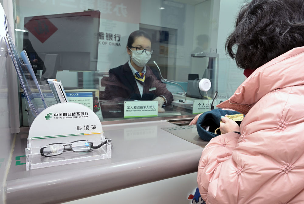 2月10日,在北京西城区中国邮政储蓄银行新街口支行,工作人员在辅助老年人办理个人业务。该行根据周边老龄人口多的特点,灵活开展柜员服务、设置辅助应急用品等便民举措。